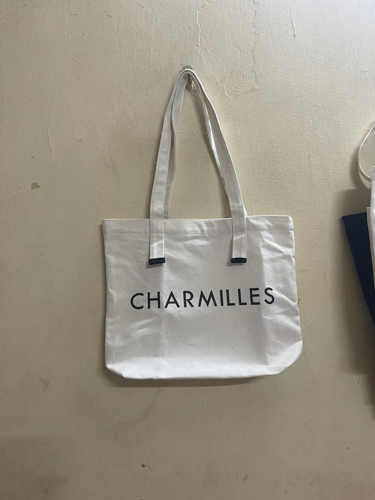 T&uacute;i vải m&agrave;u s&aacute;ng với quai d&agrave;i v&agrave; chữ CHARMILLES tr&ecirc;n mặt trước