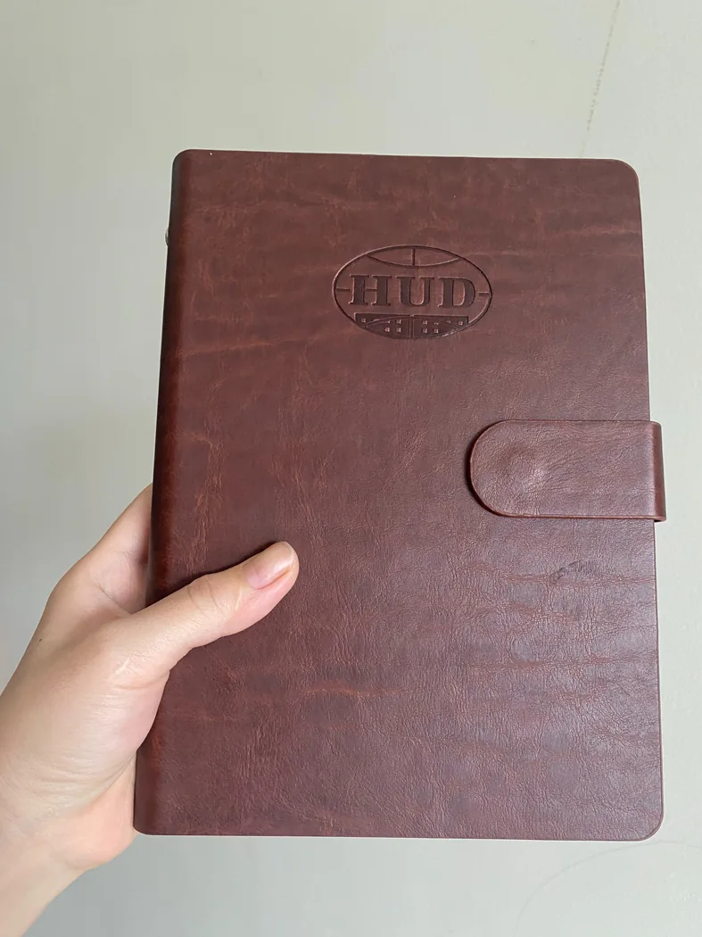 Cận cảnh biểu trưng ch&igrave;m c&ugrave;ng m&agrave;u b&igrave;a tr&ecirc;n sổ m&agrave;u n&acirc;u đỏ