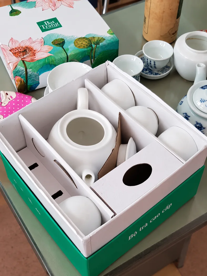 Hộp bộ tr&agrave; xanh mở, c&aacute;c m&oacute;n sứ được chia bằng v&aacute;ch ngăn trắng