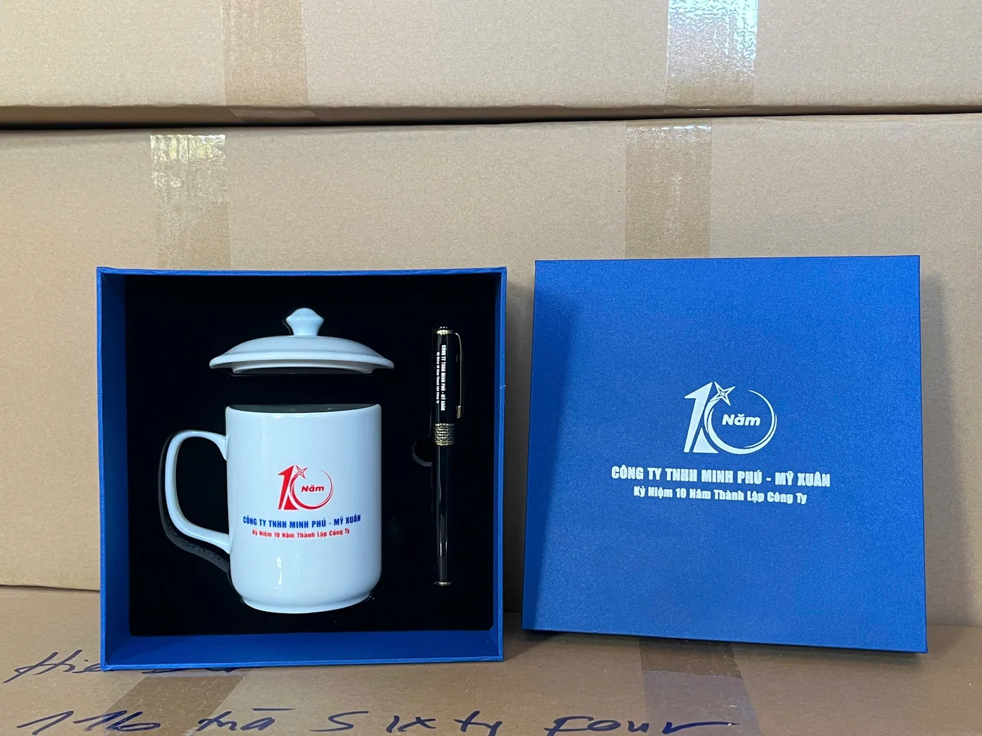 Bộ cốc b&uacute;t in logo trong hộp mở đặt trước c&aacute;c kiện carton