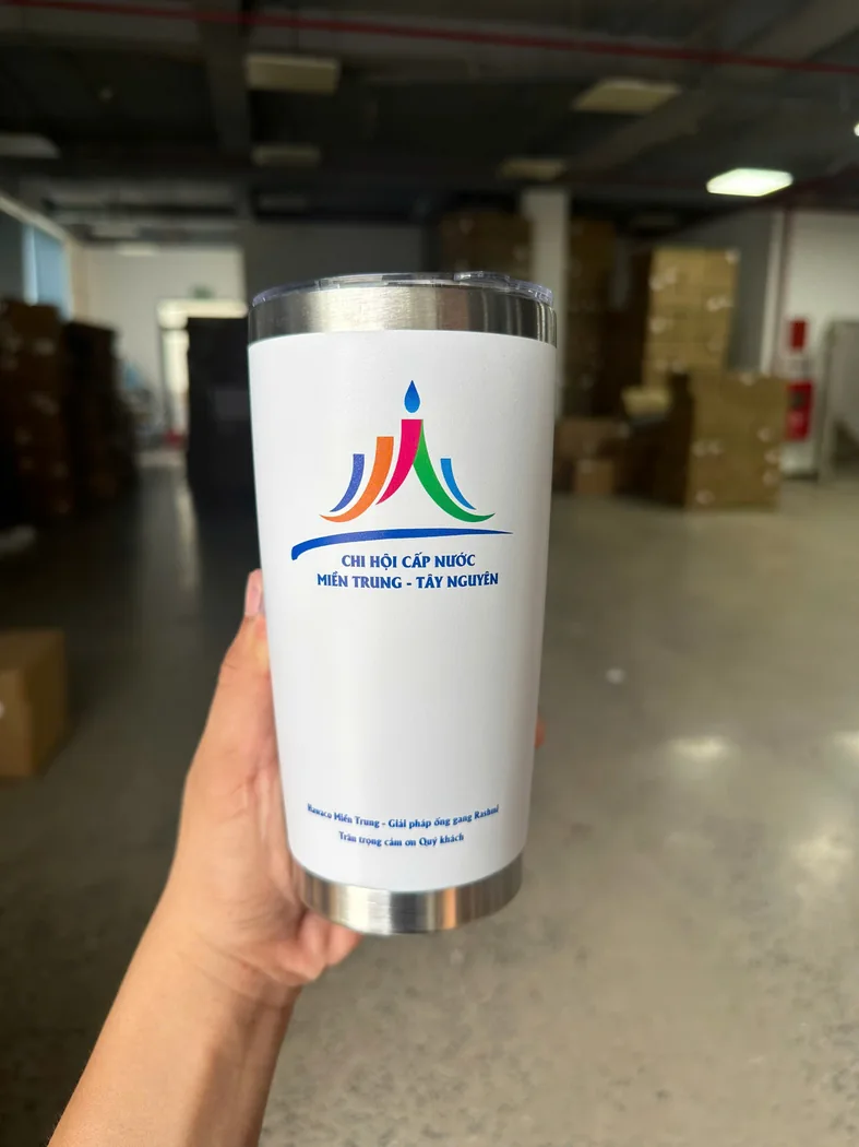Cốc giữ nhiệt trắng c&oacute; logo đơn vị cấp nước in tr&ecirc;n th&acirc;n được cầm tr&ecirc;n tay