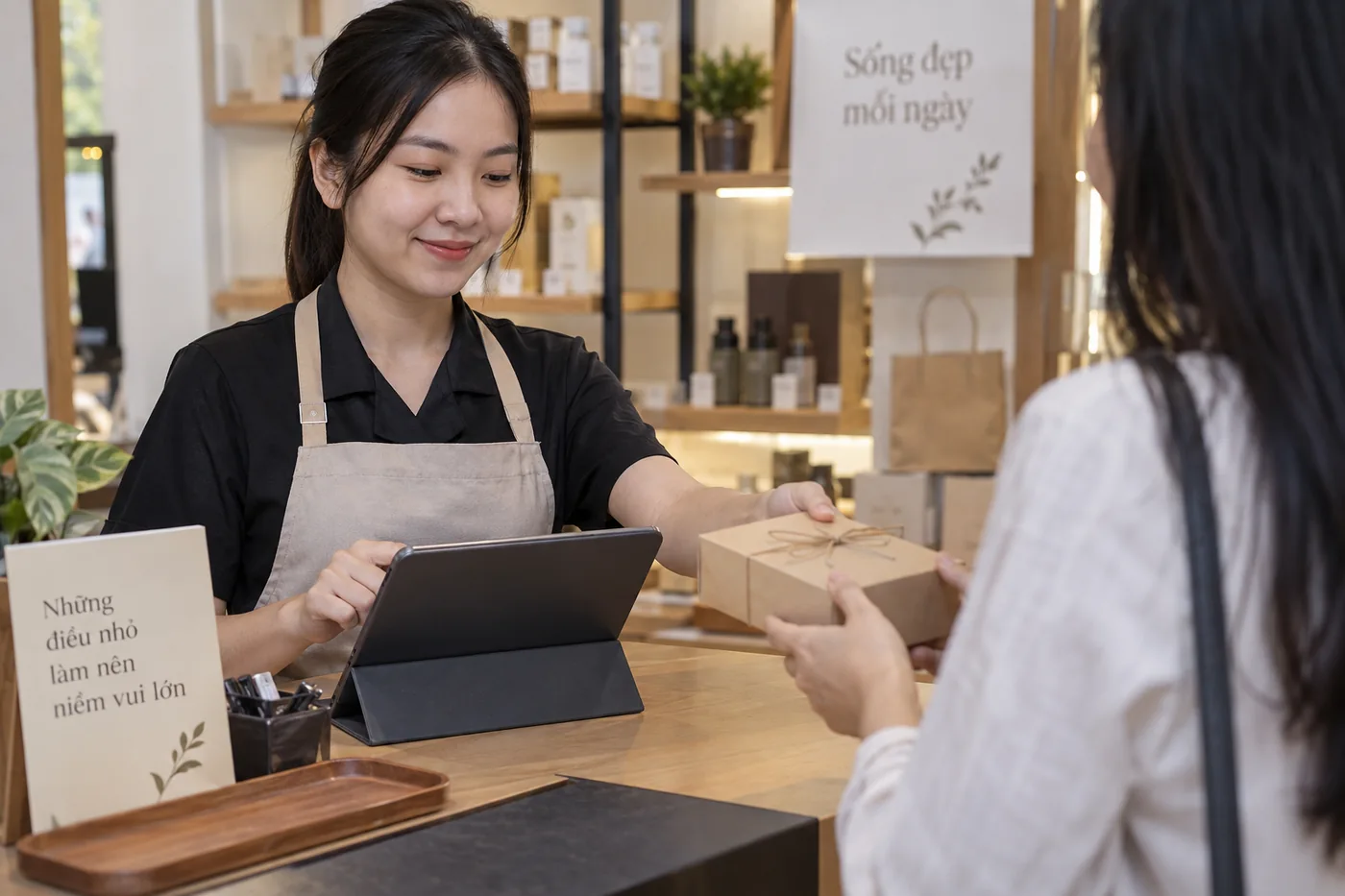 Nh&acirc;n vi&ecirc;n thao t&aacute;c tr&ecirc;n m&aacute;y t&iacute;nh bảng khi trao hộp qu&agrave;