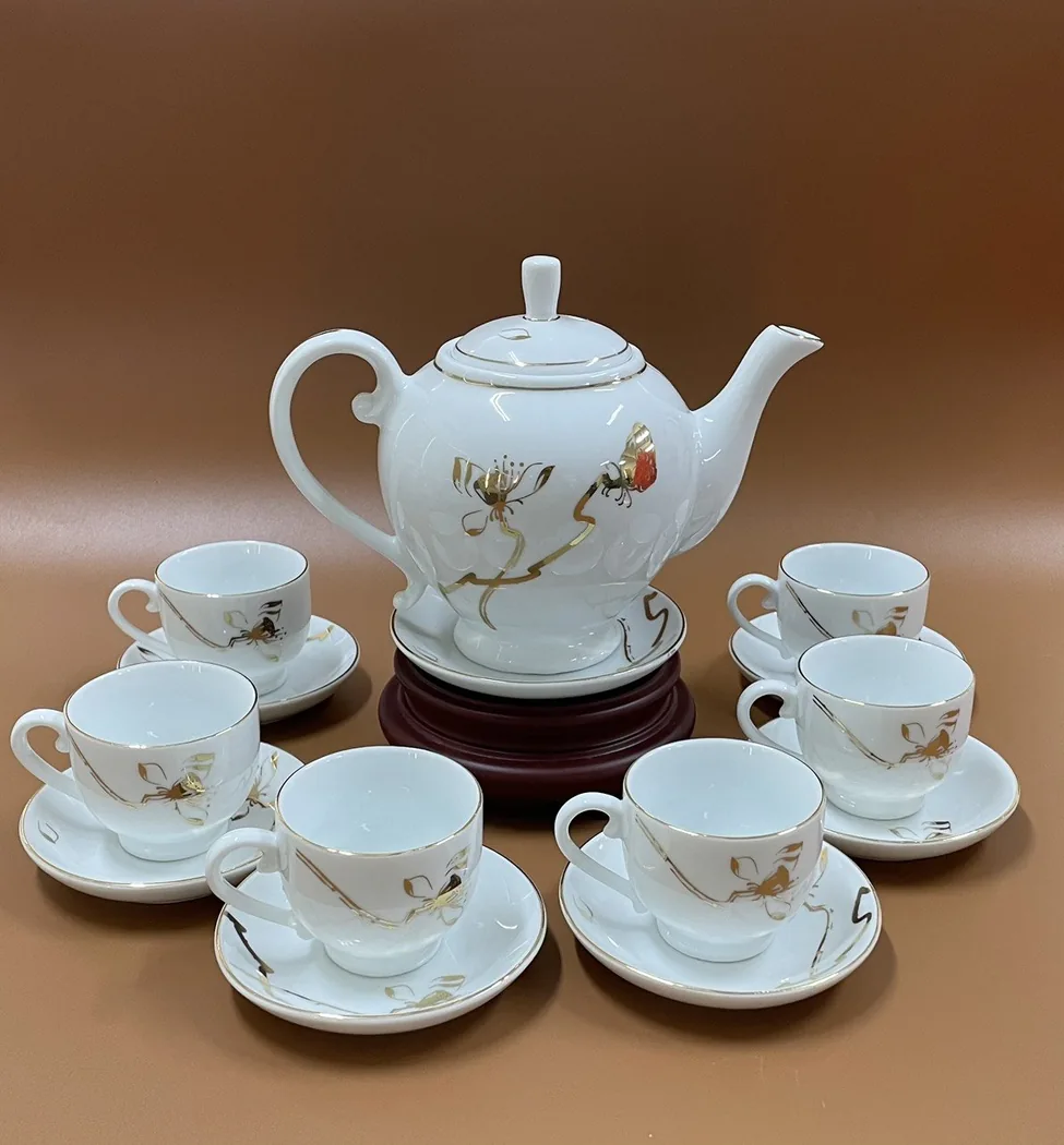 Ấm sứ men trắng c&oacute; nắp đặt c&ugrave;ng ch&eacute;n v&agrave; đĩa đồng bộ