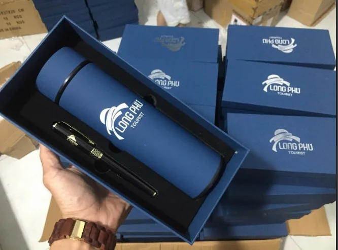 Một hộp b&igrave;nh v&agrave; b&uacute;t in dấu Long Ph&uacute; đặt trước nhiều hộp xanh c&ugrave;ng mẫu