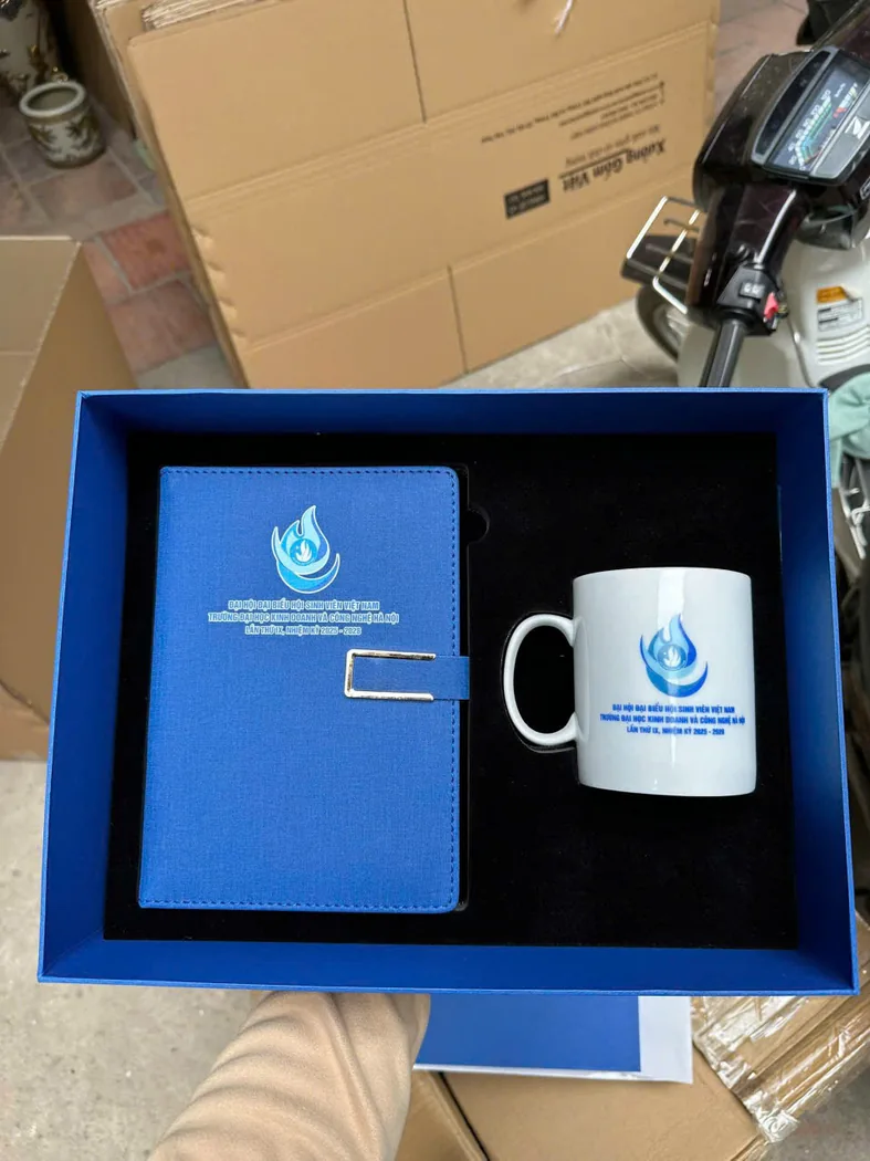 Hộp xanh chứa sổ v&agrave; cốc in c&ugrave;ng dấu đại hội trong khu vực đ&oacute;ng h&agrave;ng