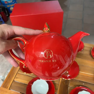 Demo logo TA Thanh An nhỏ trên ảnh cầm ấm đỏ thực tế