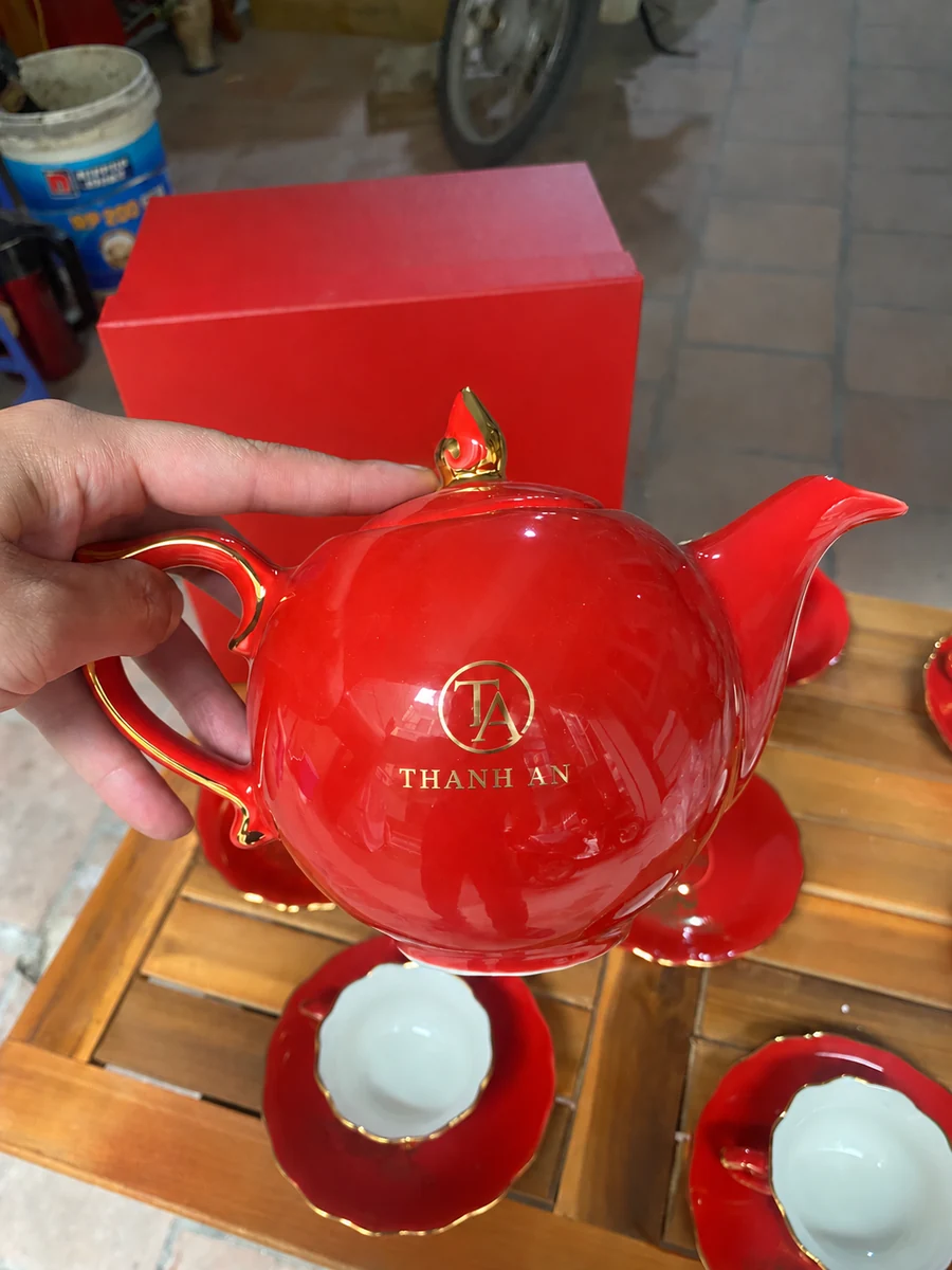 Demo logo TA Thanh An nhỏ trên ảnh cầm ấm đỏ thực tế