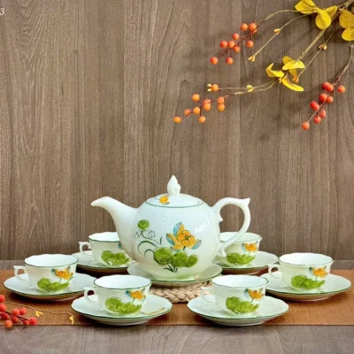 Ảnh nguồn bộ men ngọc vẽ tay hoa sen vàng với ấm và sáu chén trên bàn gỗ