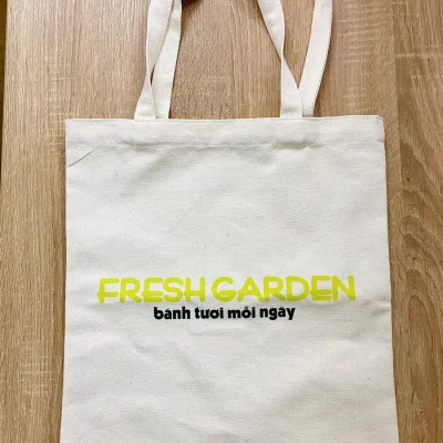 Ảnh thật túi canvas FRESH GARDEN trên nền gỗ, rõ bề mặt và quai