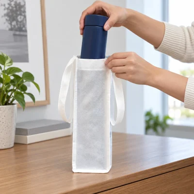 Cảnh đưa bình xanh qua miệng mở của túi không dệt trắng