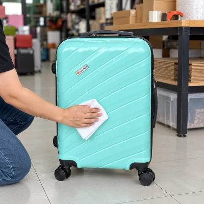 Cảnh dùng khăn mềm lau mặt vali xanh ngọc đang đóng